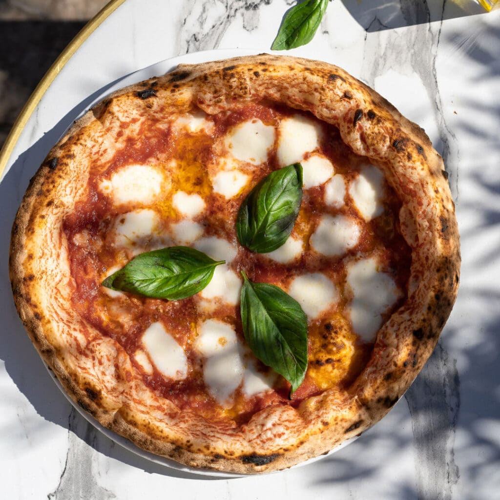 Pizza Margherita traditionnelle avec sauce tomate San Marzano, mozzarella fior di latte fondue et feuilles de basilic frais, servie chez 500 Degrés dans les Grandes Halles du Vieux-Port à Marseille.